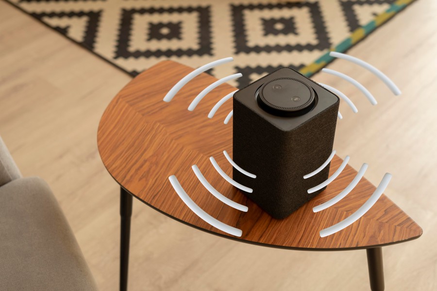 Modern black subwoofer speaker producing sound waves on a wooden table