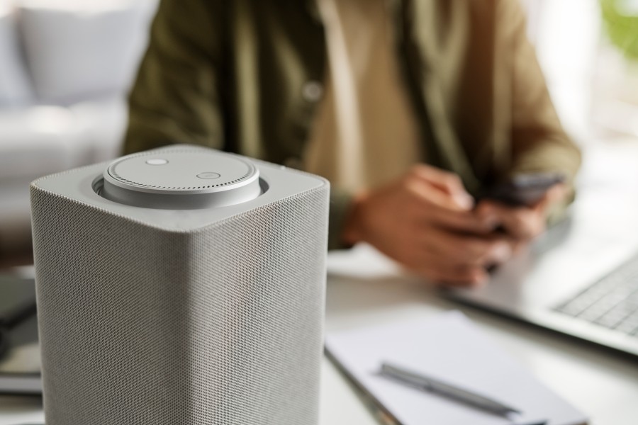 Portable smart Bluetooth speaker on a desk with a person using a smartphone